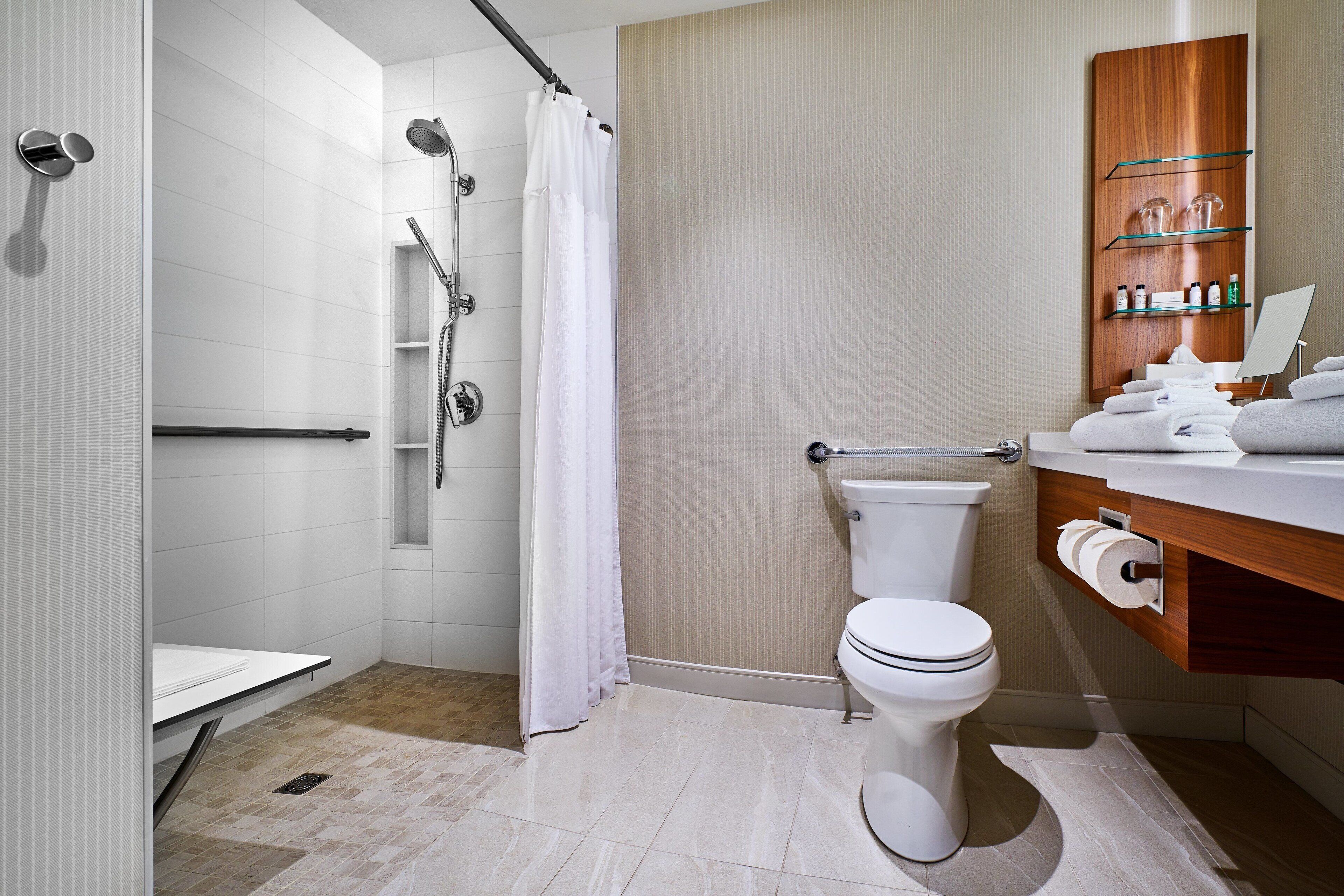 Un baño moderno con ducha, inodoro y tocador con estantes.