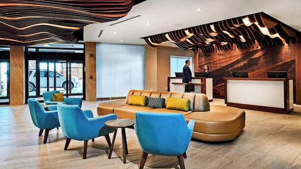 A modern lobby with a reception desk, blue seating area, and a large window. - Delta Hotels by Marriott Dartmouth (Dartmouth)