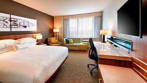 A hotel room with a large bed, a desk, a chair, a sofa, a TV, and a window with curtains. - Delta Hotels by Marriott Dartmouth (Dartmouth)