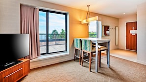 A hotel room with a large window, a television, a small table with chairs, and a door. - Delta Hotels by Marriott Dartmouth (Dartmouth)