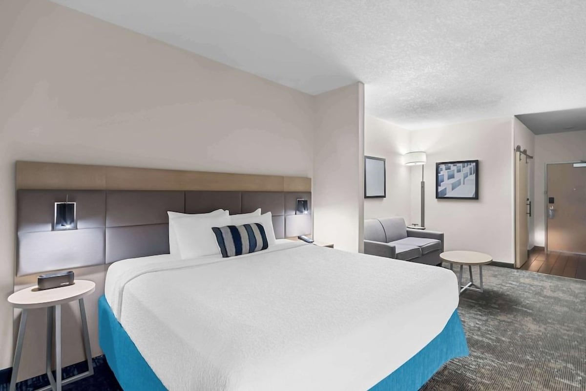 A modern hotel room with a large bed, a desk, and a chair.