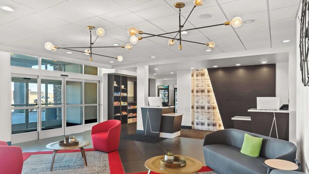 Eine moderne Lobby mit Sitzbereichen, einem Empfangsbereich und einer Treppe.
