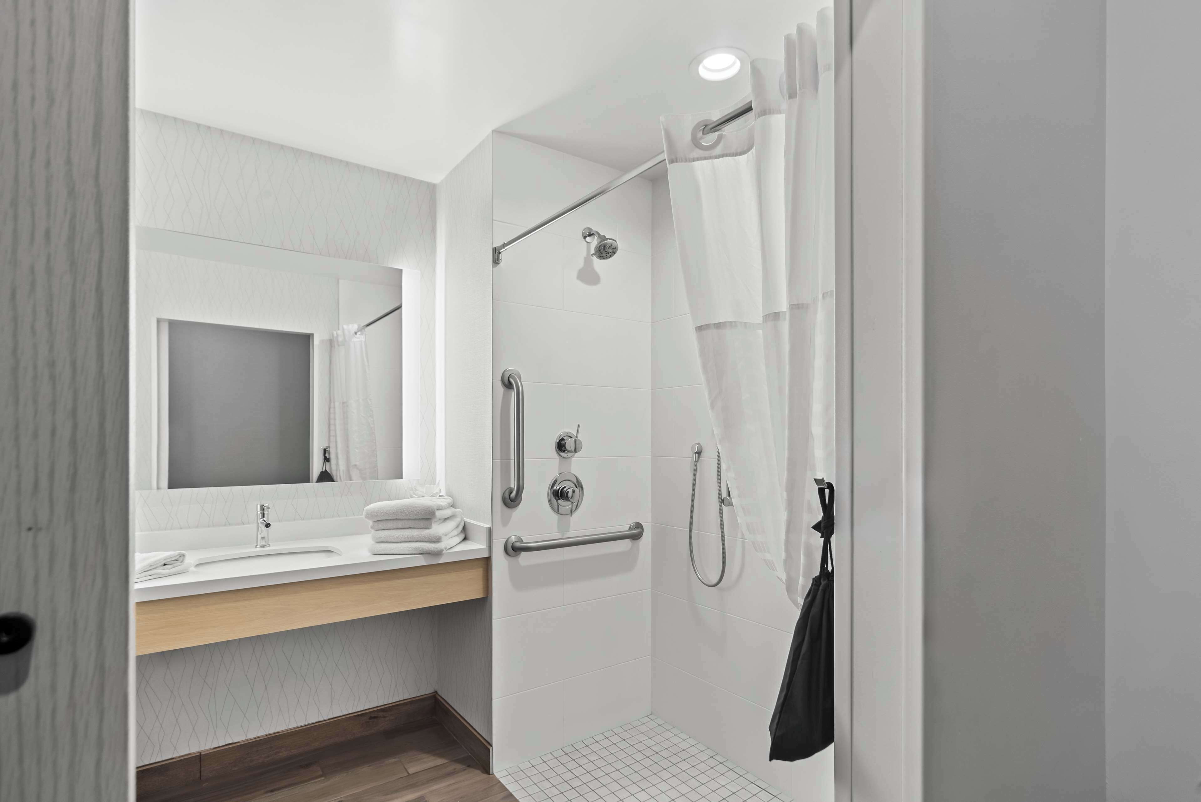 A modern bathroom with a shower, a sink, and a mirror.