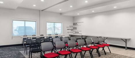 A conference room with rows of chairs, a projector screen, and motivational quotes on the wall.