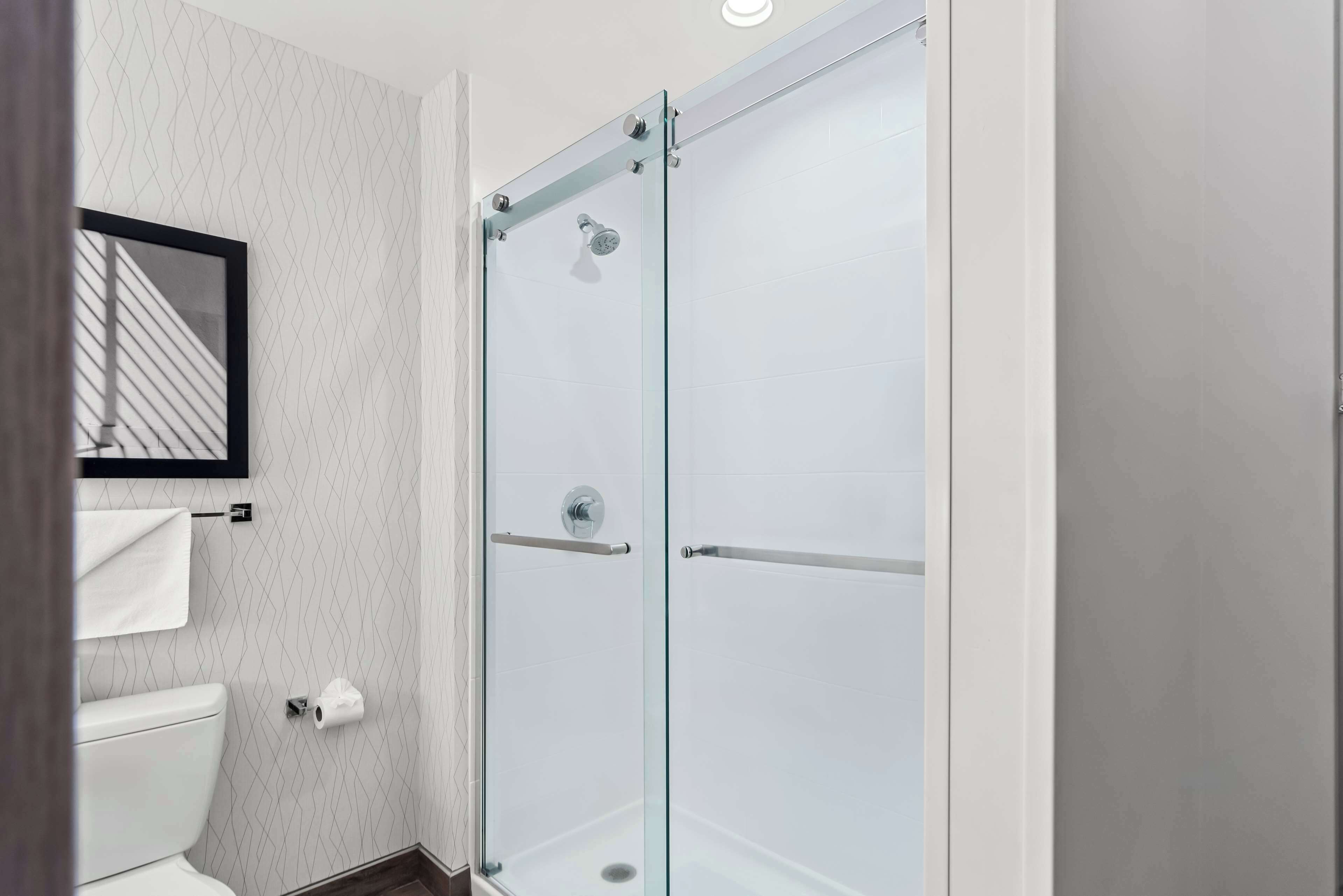 Un baño moderno con cabina de ducha de vidrio, inodoro y perchero para toallas.