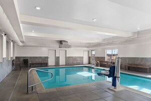 Una piscina interior con agua cristalina, un trampolín y una silla para salvavidas.