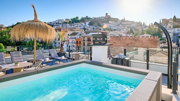 A rooftop pool with lounge chairs, a thatched umbrella, and a view of a historic town. - Boutique Hotel Luna Triunfo Granada *NEW* (Granada)
