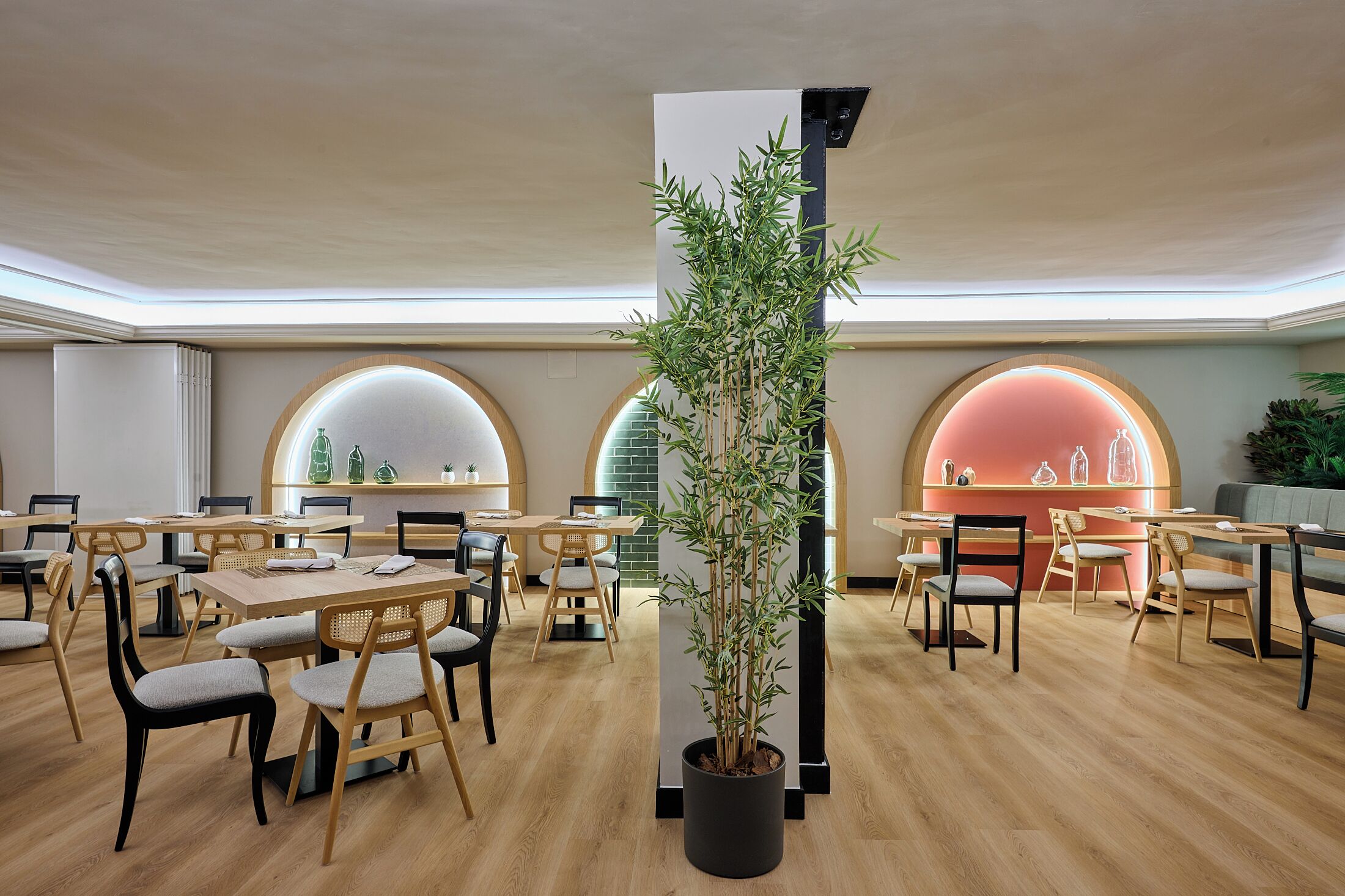 A modern dining area with round tables, chairs, and a central potted plant.