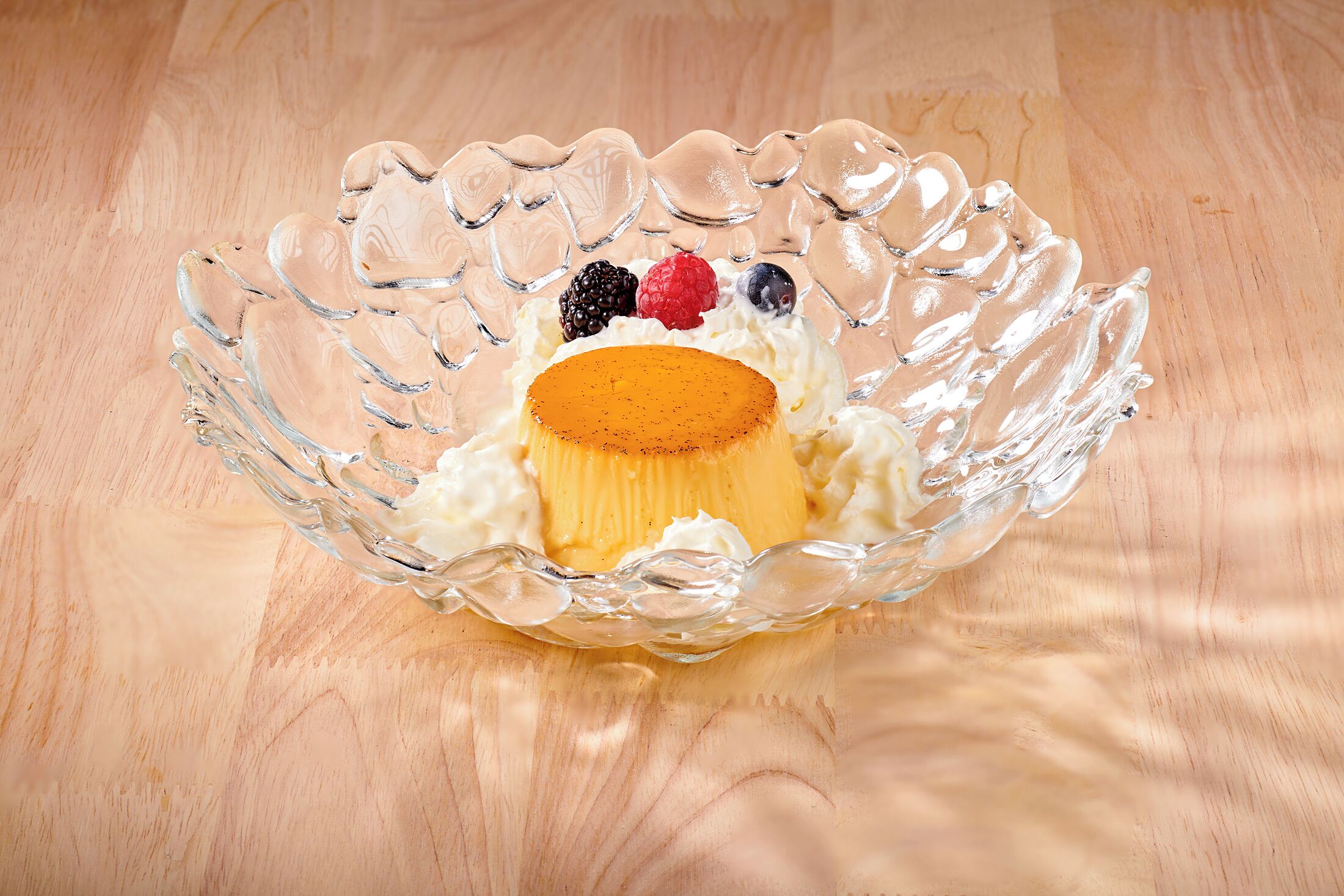 A clear glass bowl with a dessert on a wooden surface.