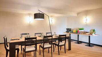 Ein moderner Essbereich mit einem langen Tisch, dunklen Stühlen, einer schwarzen Stehlampe und Wandleuchten.