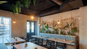 A restaurant with wooden tables and black chairs, a brick wall, and hanging plants. - Boutique Hotel Luna Triunfo Granada *NEW* (Granada)