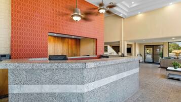 A reception area with a marble counter, a wooden panel wall, and a ceiling fan.