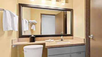 A bathroom with a large mirror, a sink, a toilet, and a towel rack.