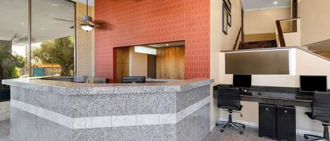 A reception area with a granite counter, a staircase, and a desk with office chairs.