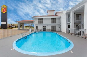 Un hotel con piscina, un letrero de Super 8 y un edificio de dos pisos con balcones.