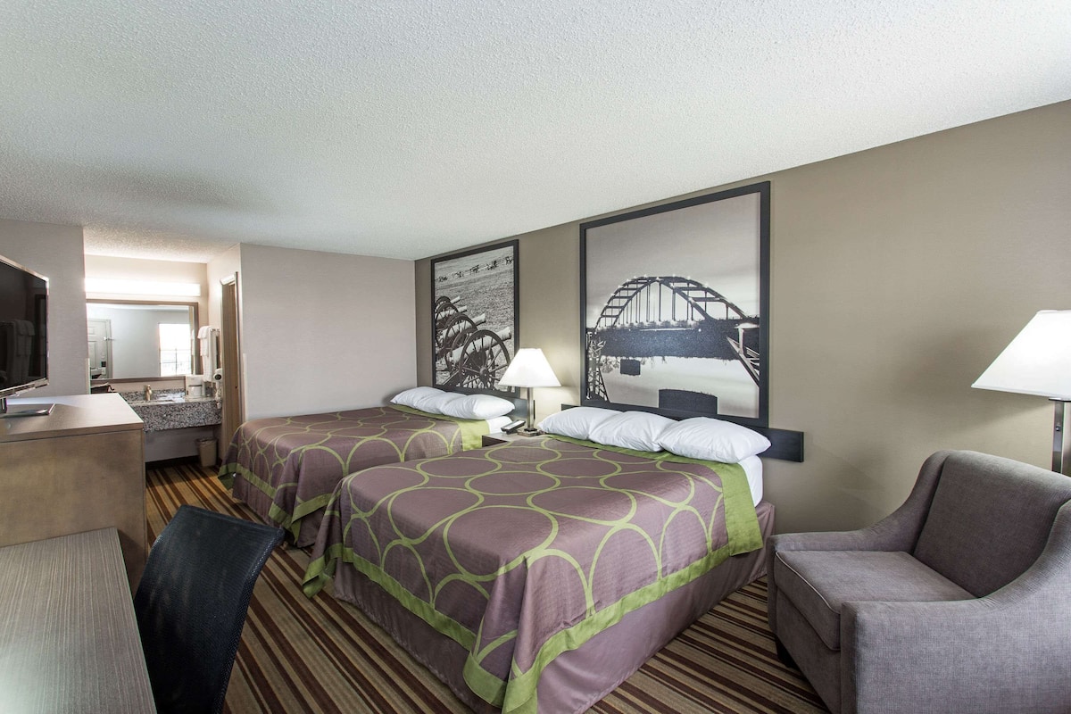 Une chambre d’hôtel avec deux lits, un bureau, une chaise et un téléviseur.