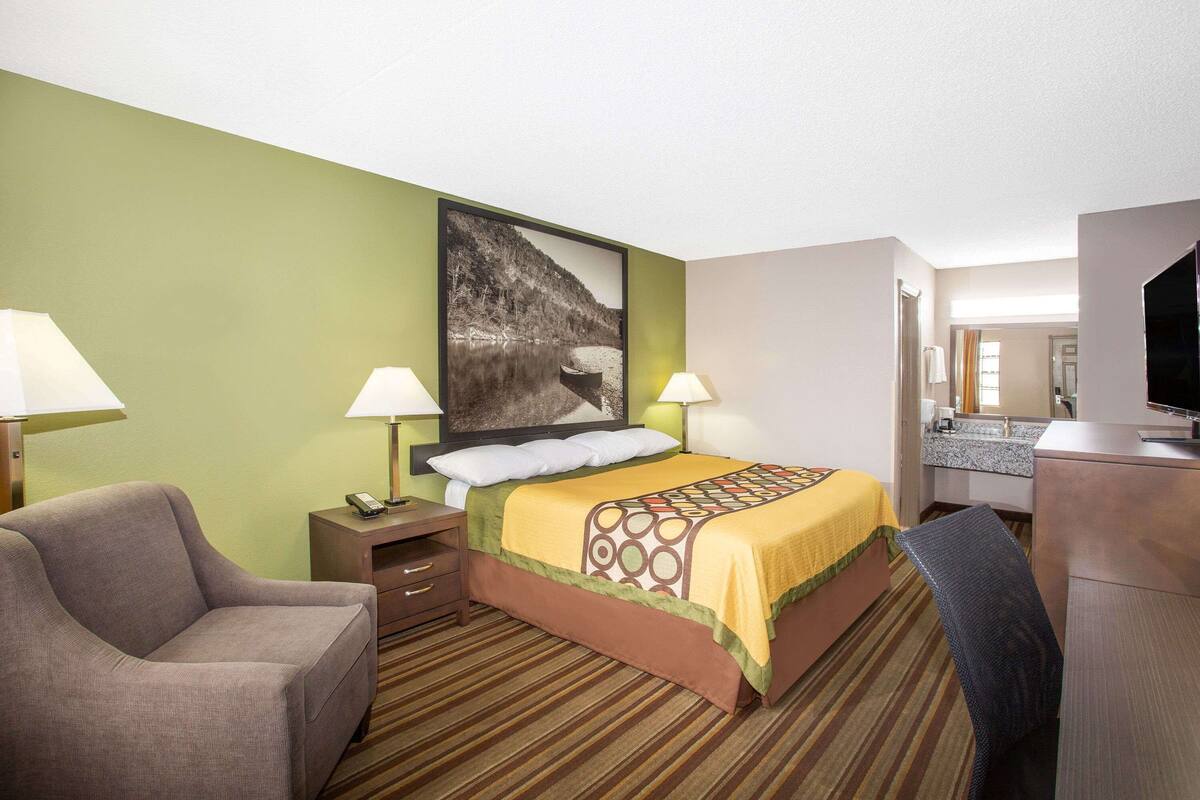 Une chambre d’hôtel comprenant un lit, deux lampes de chevet, une chaise, un bureau et un téléviseur.
