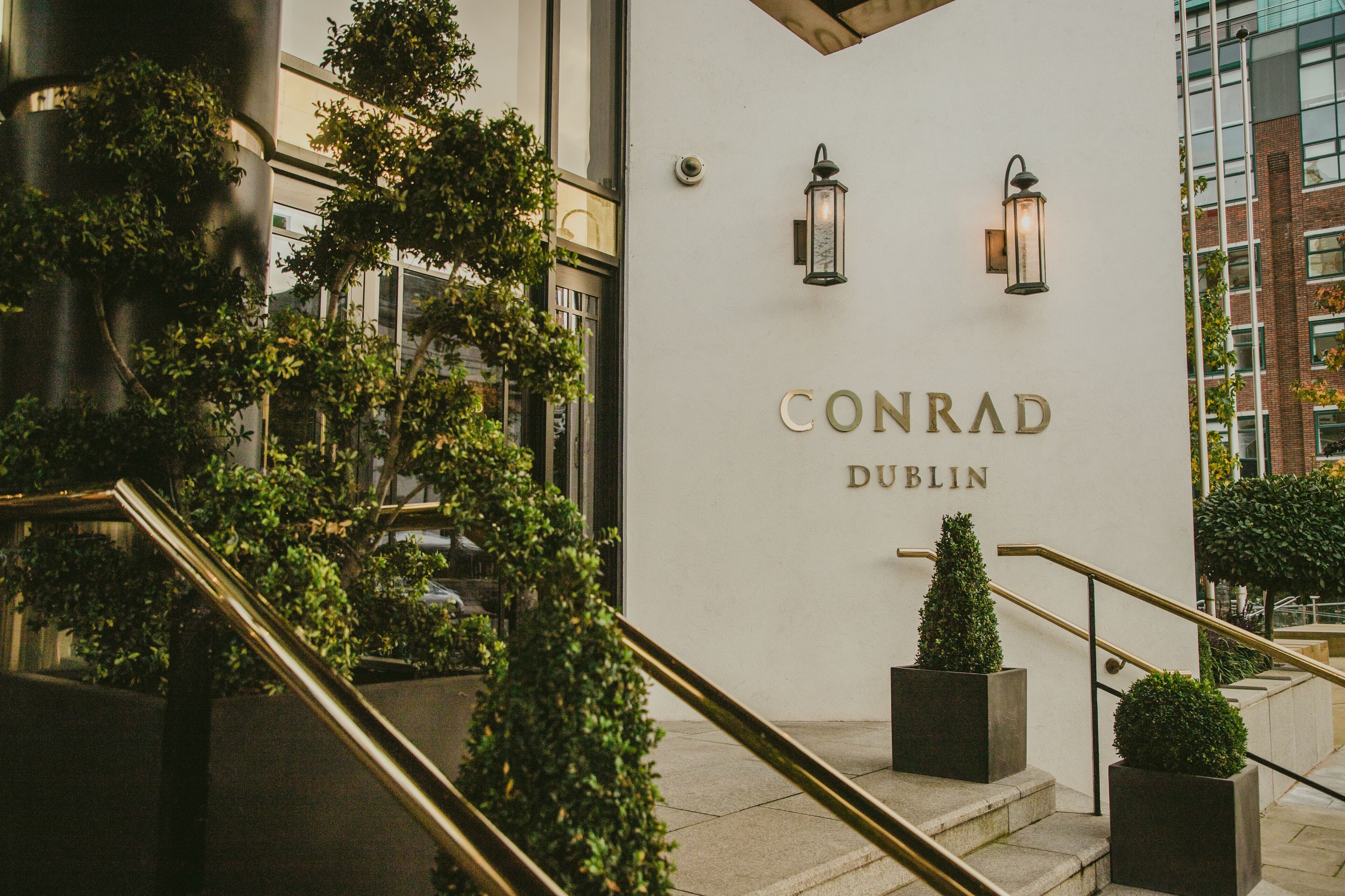A building entrance with the name "CONRAD DUBLIN" and two wall-mounted lanterns.