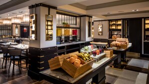 A hotel lobby with a buffet area featuring fruits and beverages.