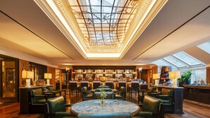 A spacious bar area with a high ceiling and skylights, surrounded by leather seating and a central marble table. - Conrad Dublin (Dublin)
