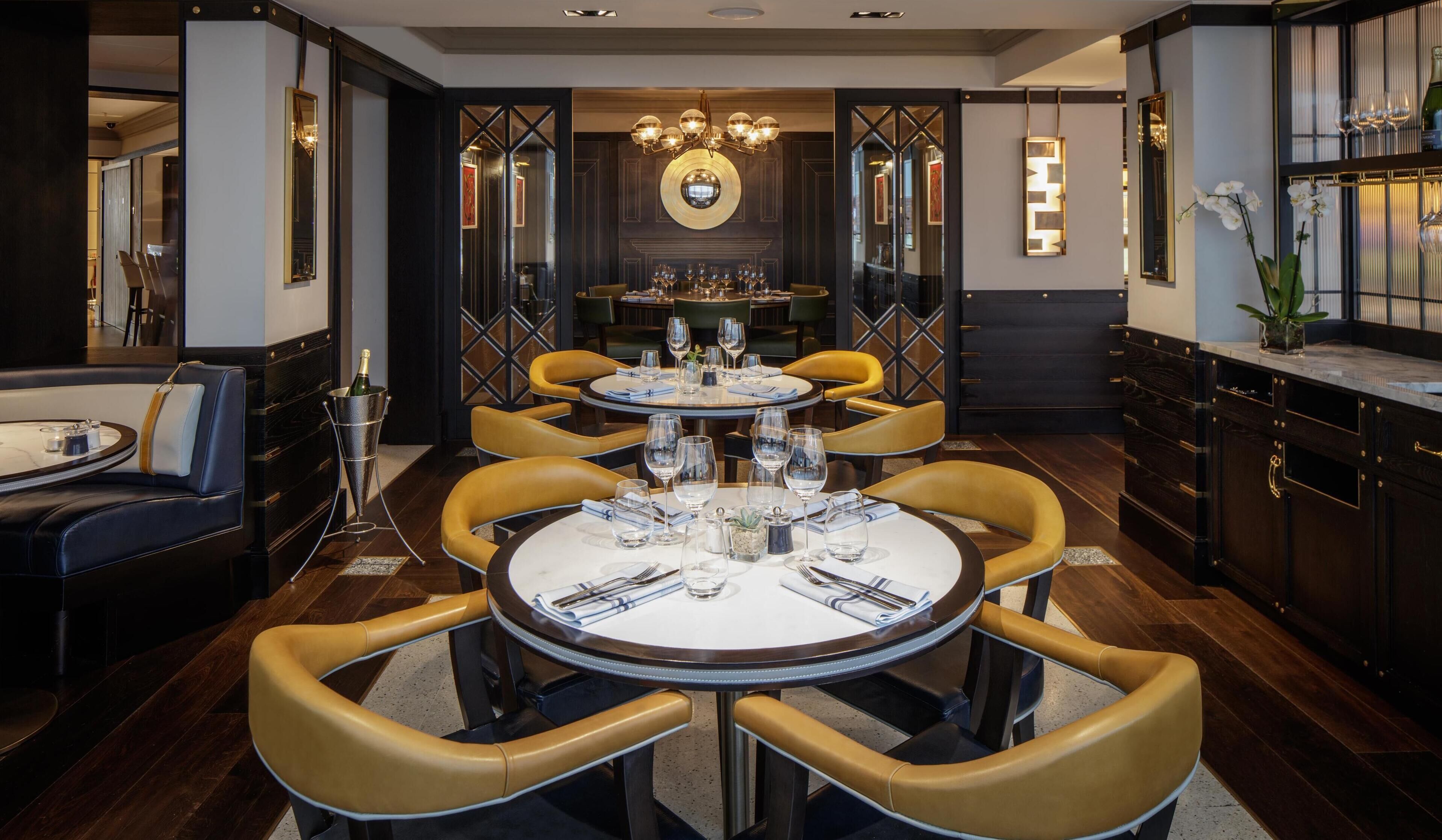 A dining area with a round table set for six, surrounded by yellow chairs.