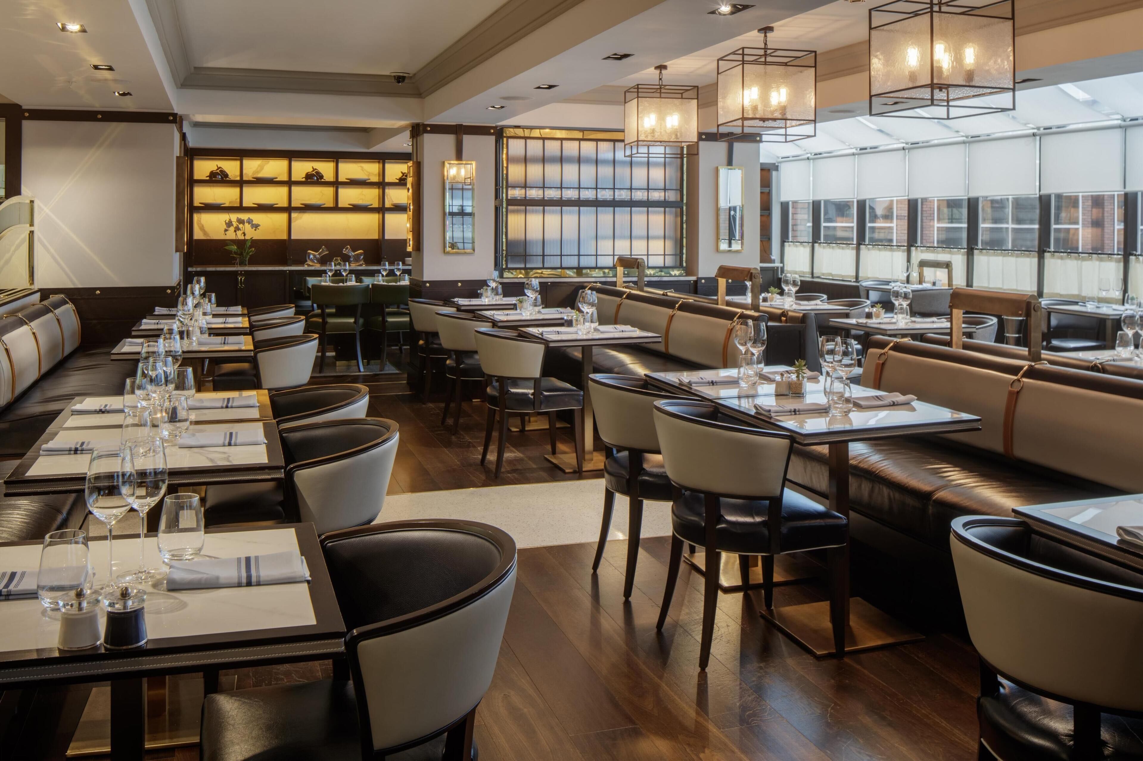 Un restaurante con varias zonas de comedor, incluyendo cabinas y mesas, con una decoración moderna y amplios ventanales.