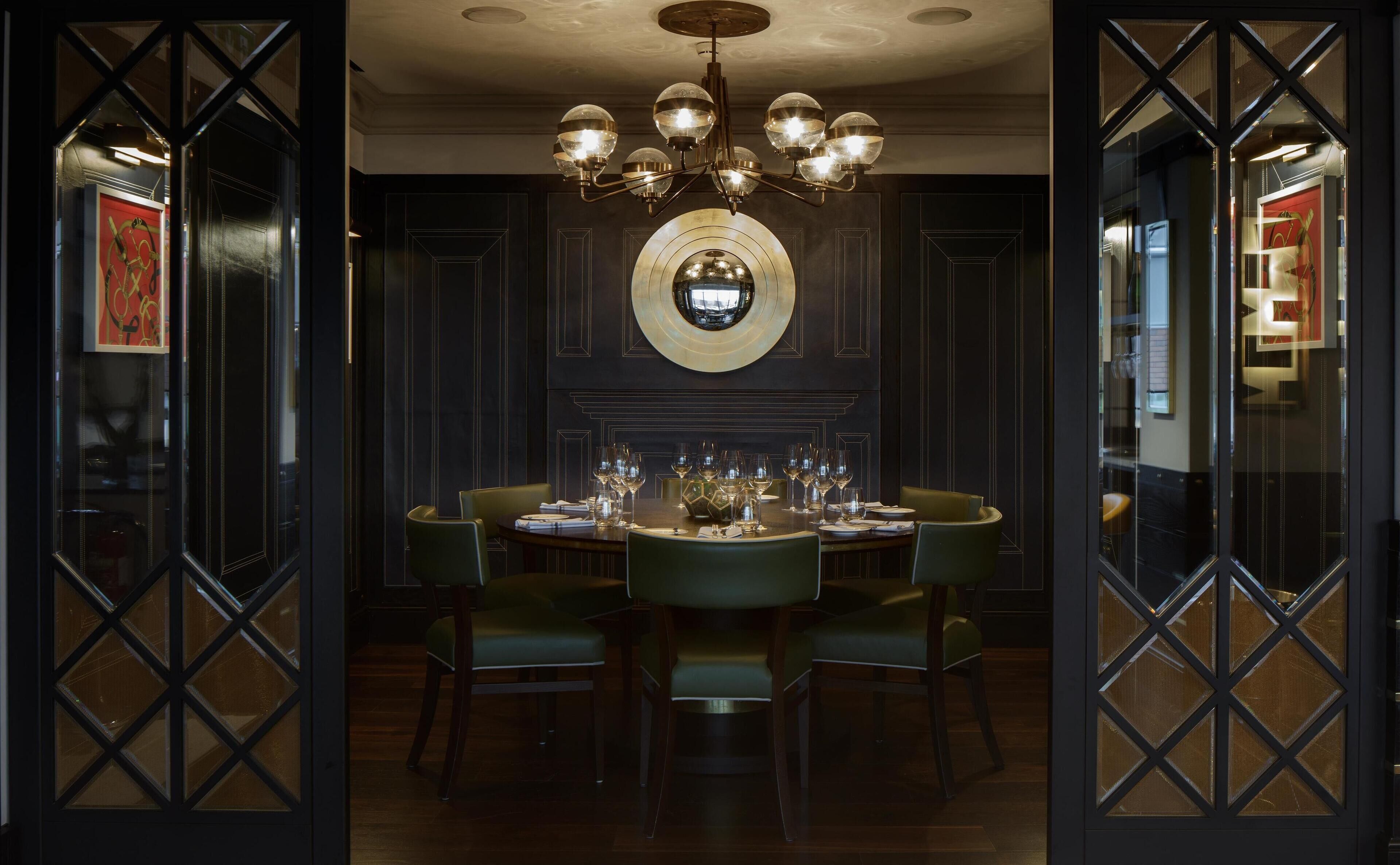 A formal dining room with a chandelier, a round mirror, and a table set for six.