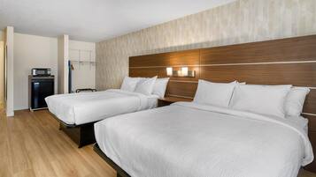 Een hotelkamer met twee bedden, een houten hoofdbord en een klein bureau met een magnetron.