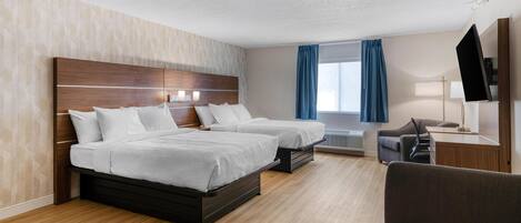 Habitación de hotel con dos camas, un escritorio, una silla y un televisor.