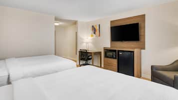 A hotel room with two beds, a desk, a television, and a microwave.