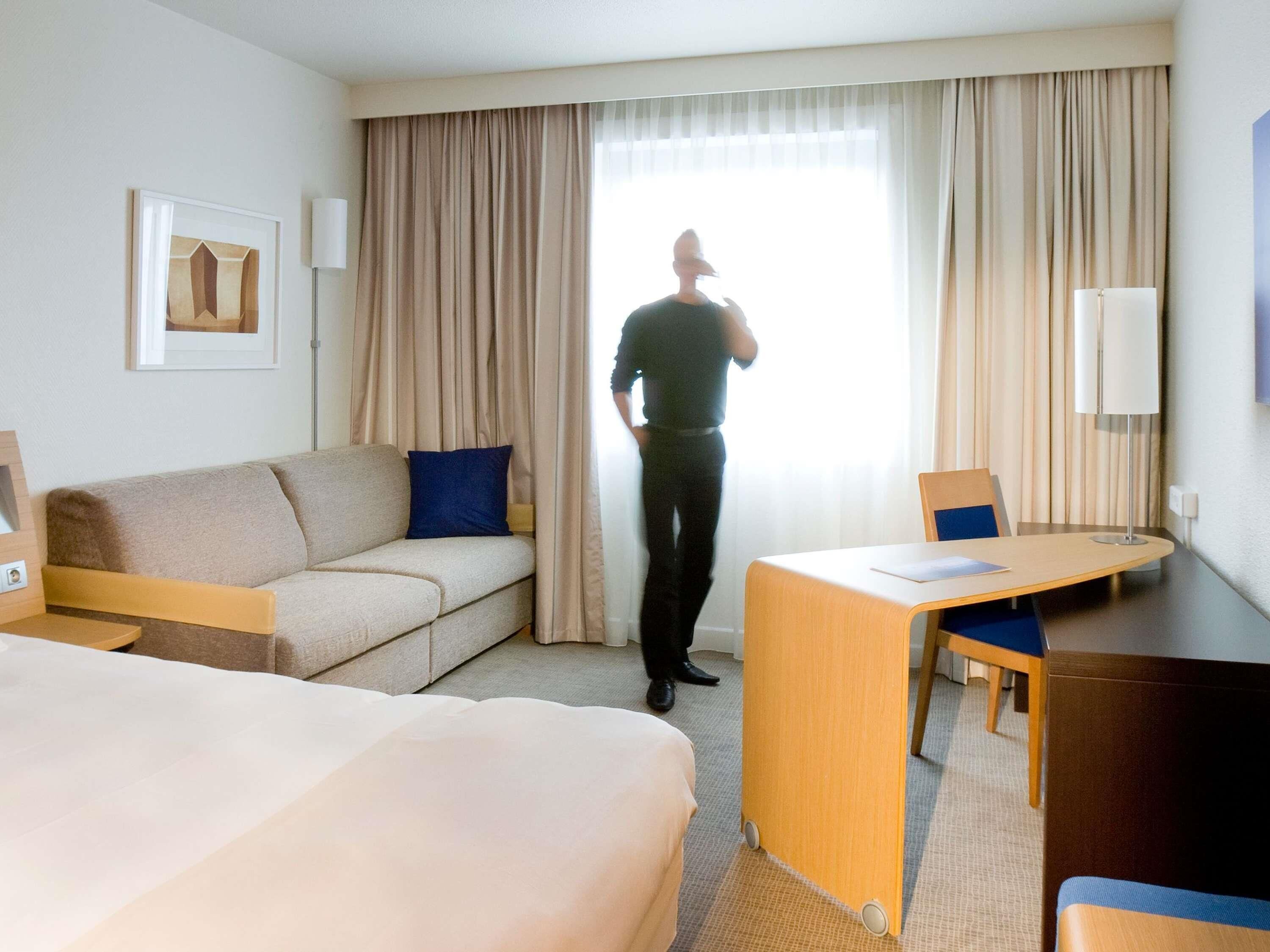Quarto de hotel com uma cama, um sofá, uma escrivaninha e uma cadeira.
