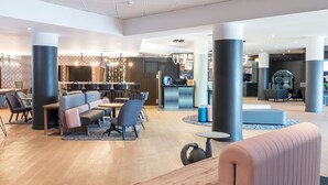 A modern lobby with a seating area, a reception desk, and a bar. - Novotel Marne-La-Vallée Noisy-Le-Grand (Noisy-le-Grand)