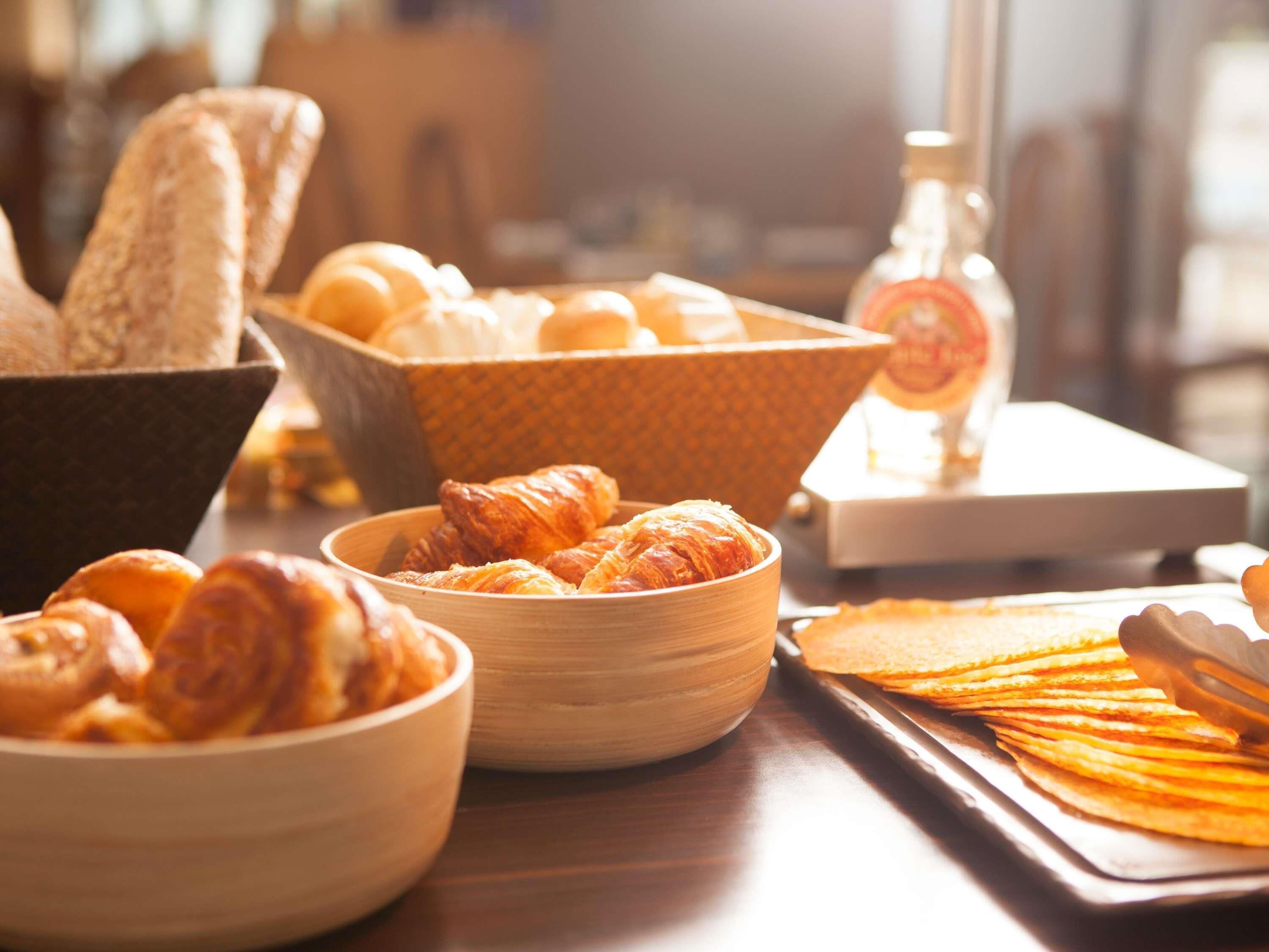 A breakfast setting with bread, croissants, and pastries on a wooden table.
