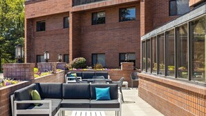 Une terrasse extérieure avec un canapé modulable, des chaises blanches et des tables.