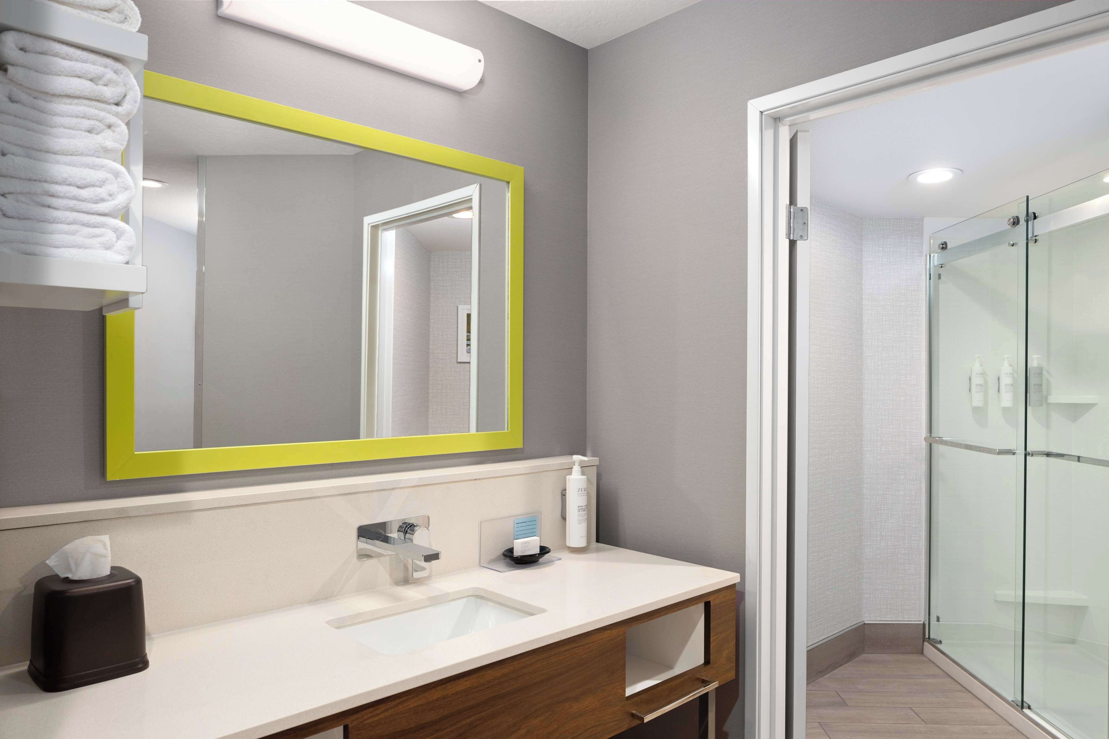 A modern bathroom with a large mirror, a sink, and a glass shower enclosure.