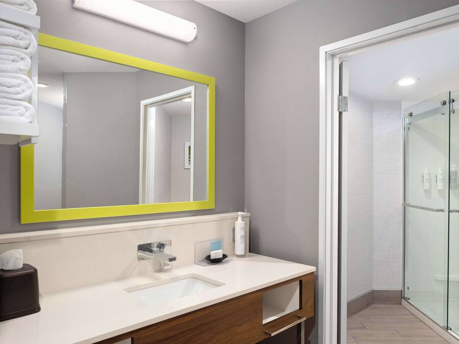 A modern bathroom with a large mirror, a sink, and a glass shower enclosure.