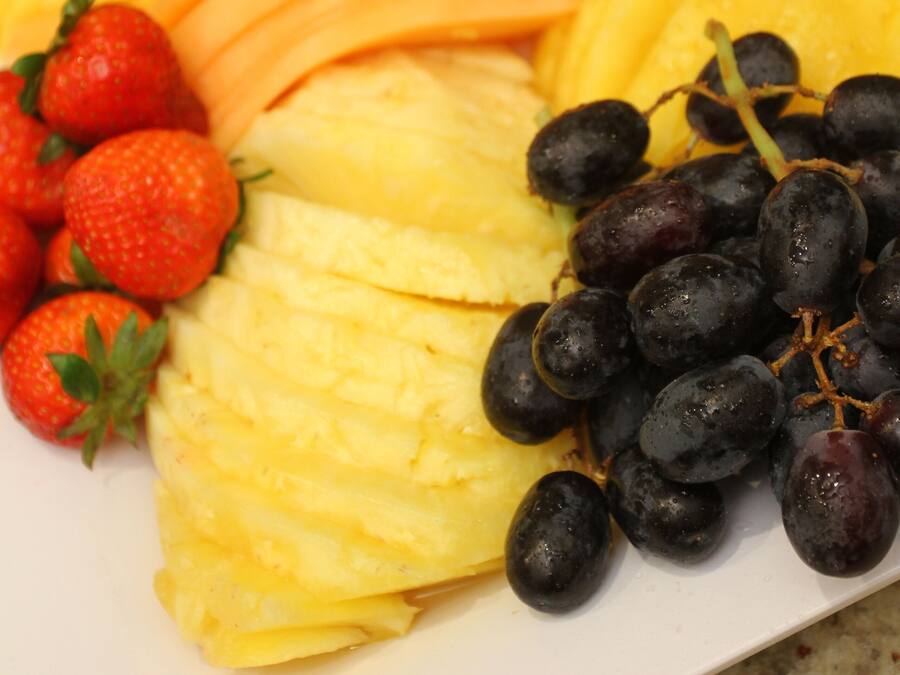 Eine Obstplatte mit Ananas, Trauben und Erdbeeren.