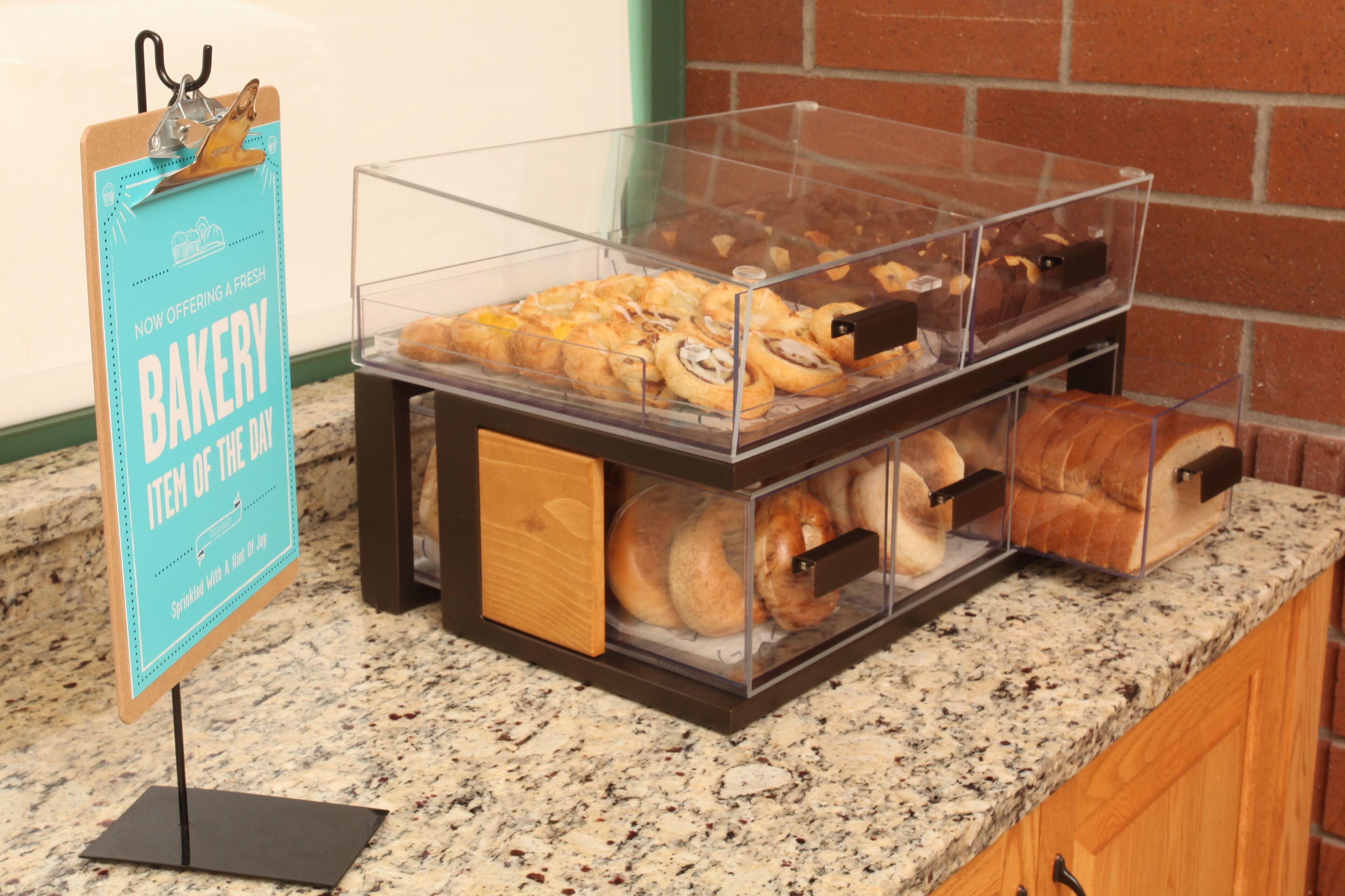 Ett bageridisplay med olika sorters bakverk presenterade i genomskinliga behållare.
