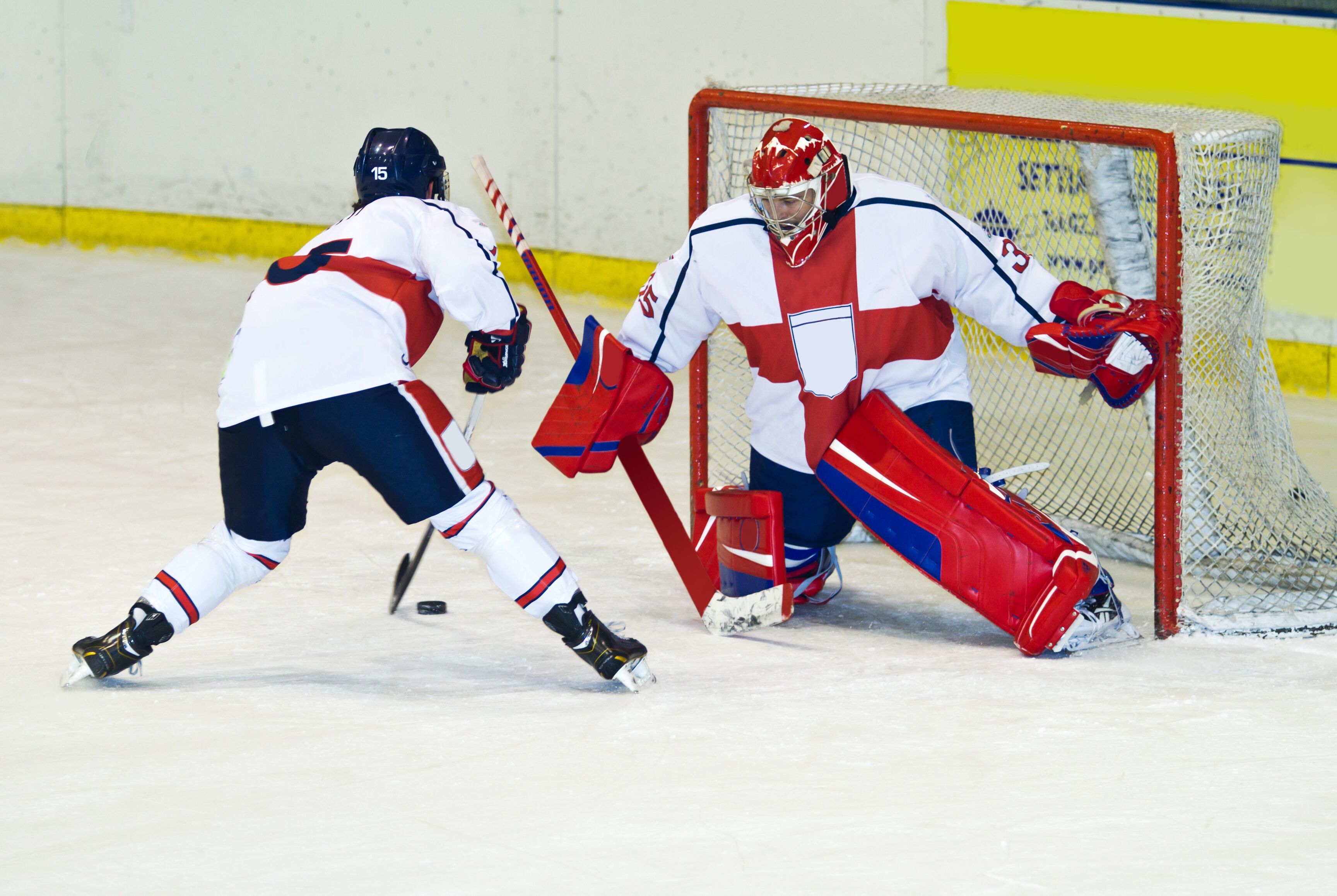 An ice hockey game in progress with players and a goalie in action.