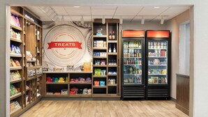 A store with shelves stocked with snacks, drinks, and other treats. There are two refrigerators labeled 'cold' and 'frozen'. - Hampton by Hilton Spokane (Spokane)