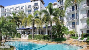 Una piscina al aire libre, sombrillas, sillones reclinables de piscina