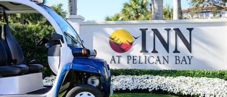 A sign for 'INN at Pelican Bay' with a logo featuring a stylized sun and palm tree.