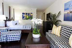 A hotel room with a bed, a sofa, a coffee table, and a potted plant.