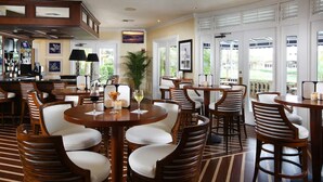 A hotel lobby with multiple seating areas, a bar, and large windows offering views of the outdoors.