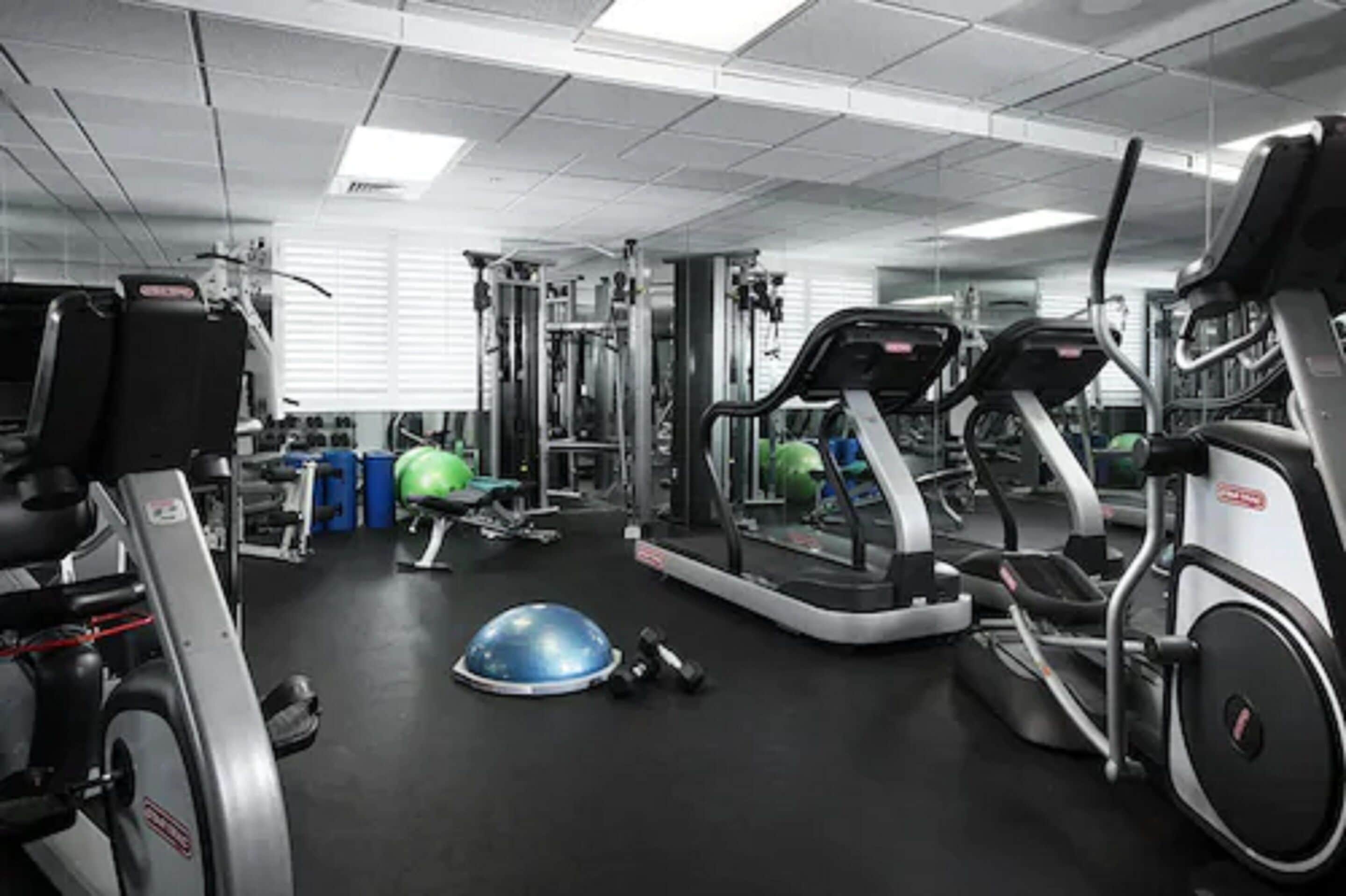 Ein Fitnessstudio mit Laufbändern, Crosstrainern und Gewichten.