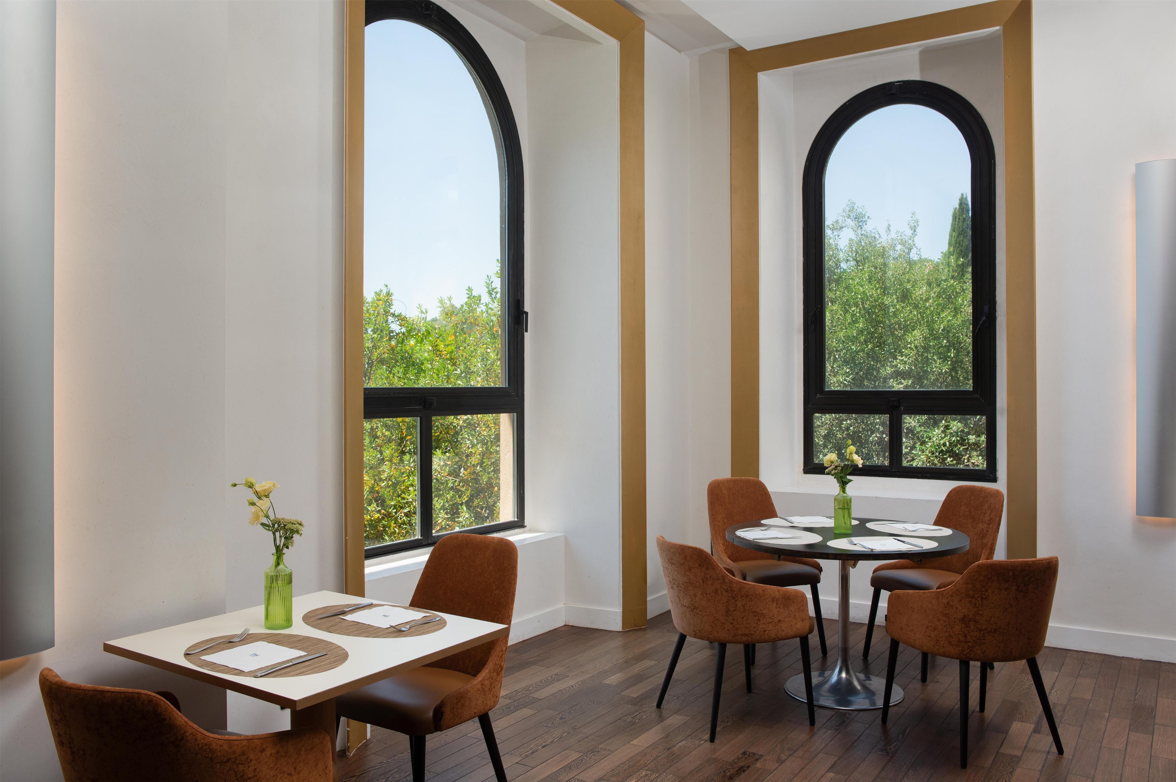 Zona pranzo con tavolo e sedie, ampie finestre e vista sul verde.