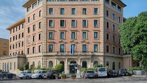 A multi-story building with a symmetrical facade, featuring a central entrance with a canopy and a sign above it.