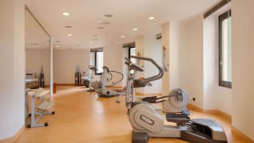 Un gimnasio moderno con máquinas de cardio, un espejo grande y suelo de madera.