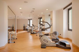 Un gimnasio moderno con máquinas de cardio, un espejo grande y suelo de madera.