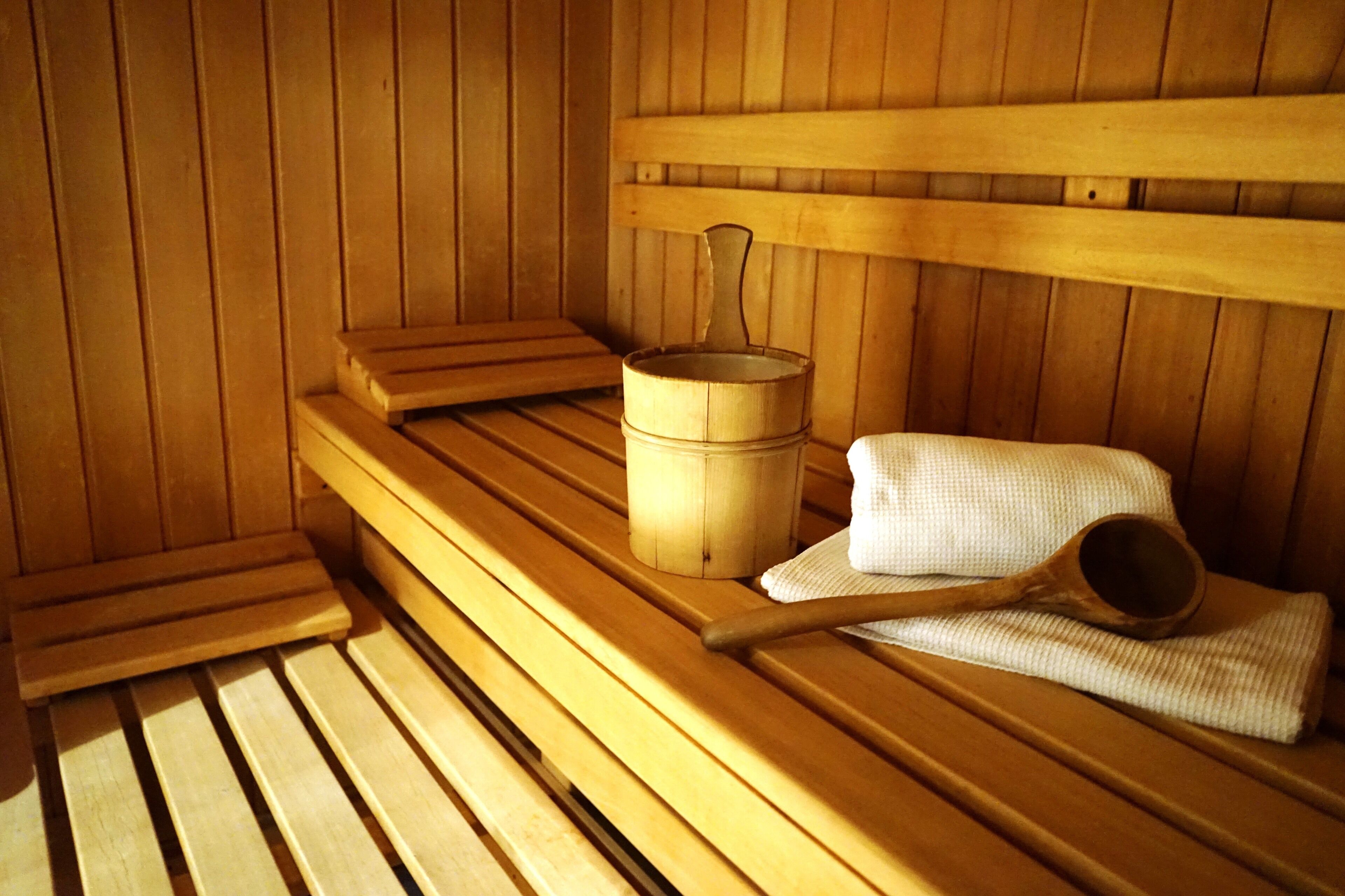 Un banco de sauna de madera con un balde y una cuchara de madera.
